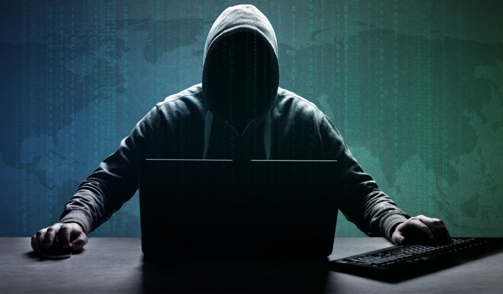 Person med luva sitter framför en laptop